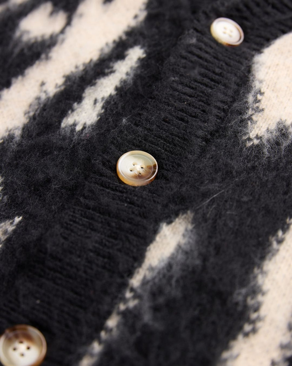 Close-up of the J Cardigan’s textured knit fabric highlighting soft, cozy fibers and subtle ribbed detailing at the neckline.