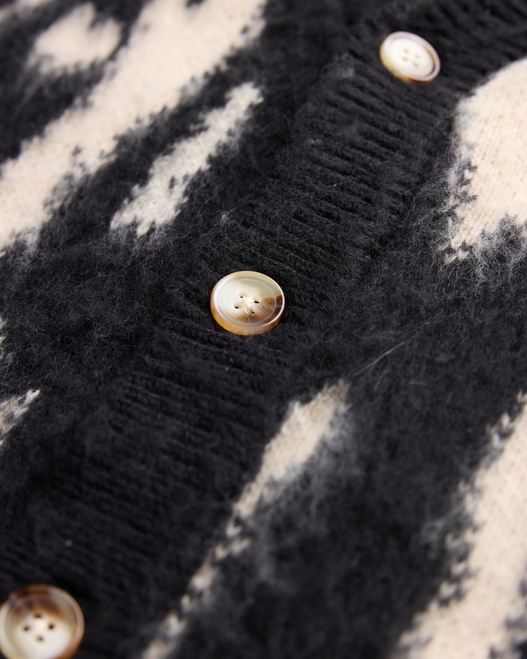 Close-up of the J Cardigan’s textured knit fabric highlighting soft, cozy fibers and subtle ribbed detailing at the neckline.