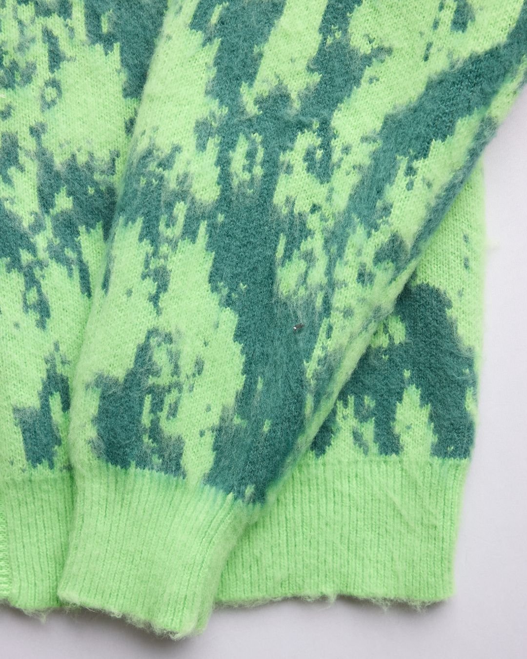 Close-up of the Grass Cardigan's textured knit fabric showcasing a relaxed fit in soft moss green from a front angled view.