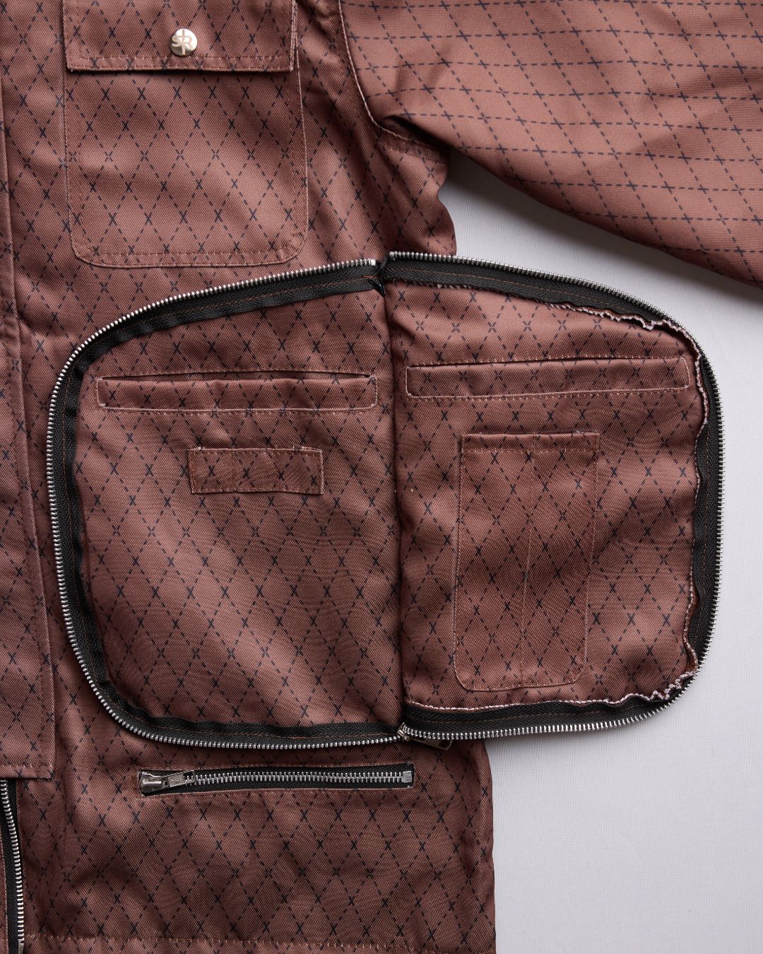 Close-up of textured waxed cotton fabric on sleeve cuff with reinforced stitching and subtle branding detail.