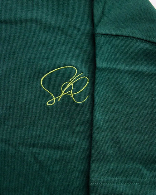 Close-up of the Green Core Streetwear shirt with golden embroidered insignia.