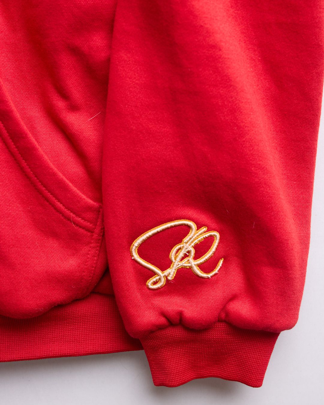 Close-up of crimson fleece fabric highlighting the soft, textured interior and reinforced stitching on the hem and cuffs.