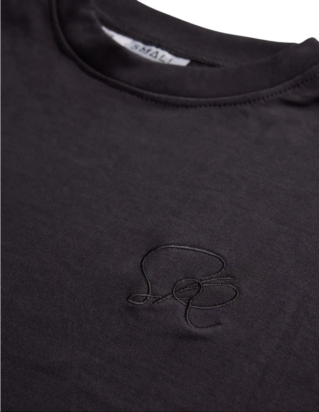 Close-up product shot of the Black Core shirt's embroidery and neckline. 