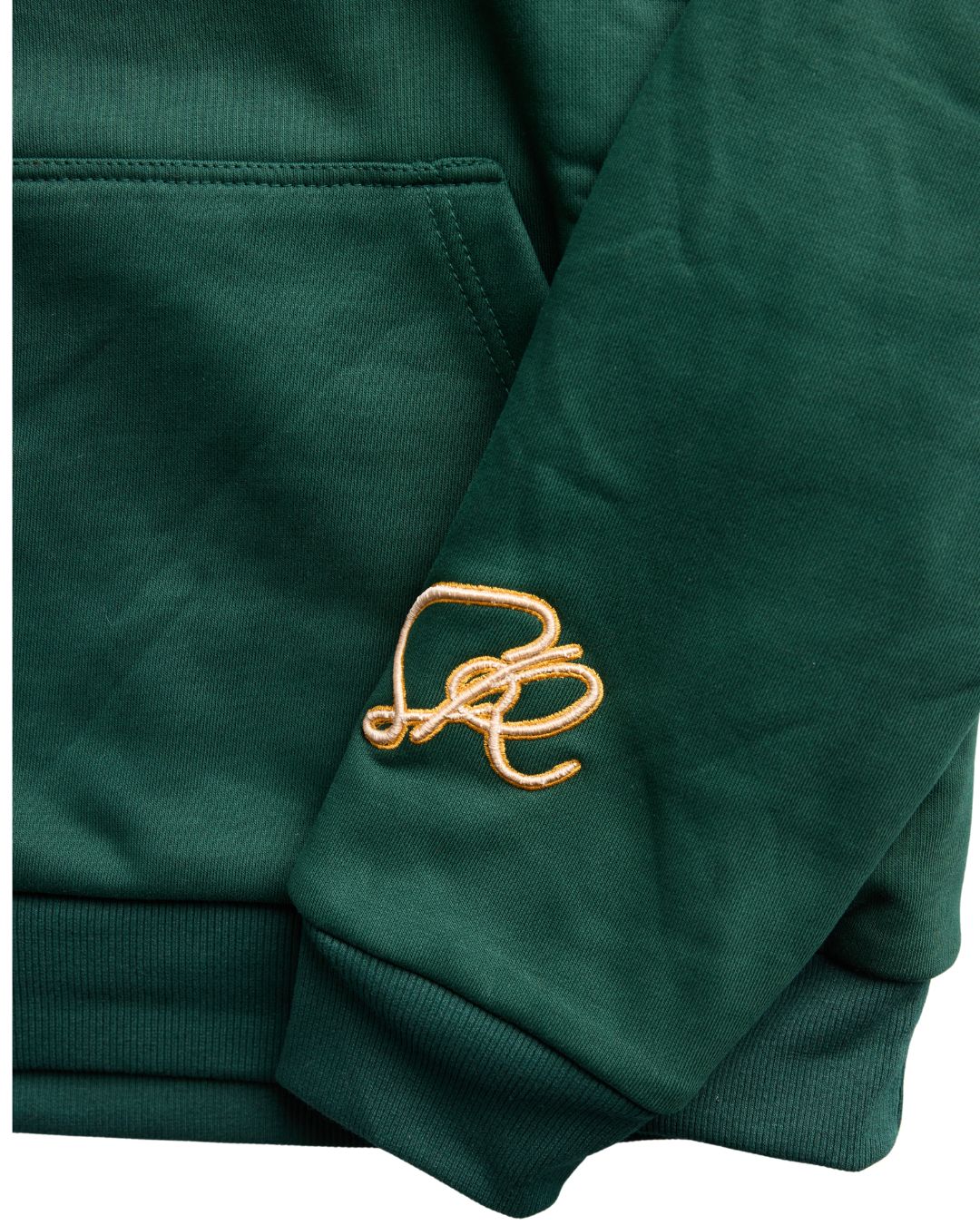 Close up of the Pine Reversable hoodie featuring embroidery on left wrist and kangaroo pockets.