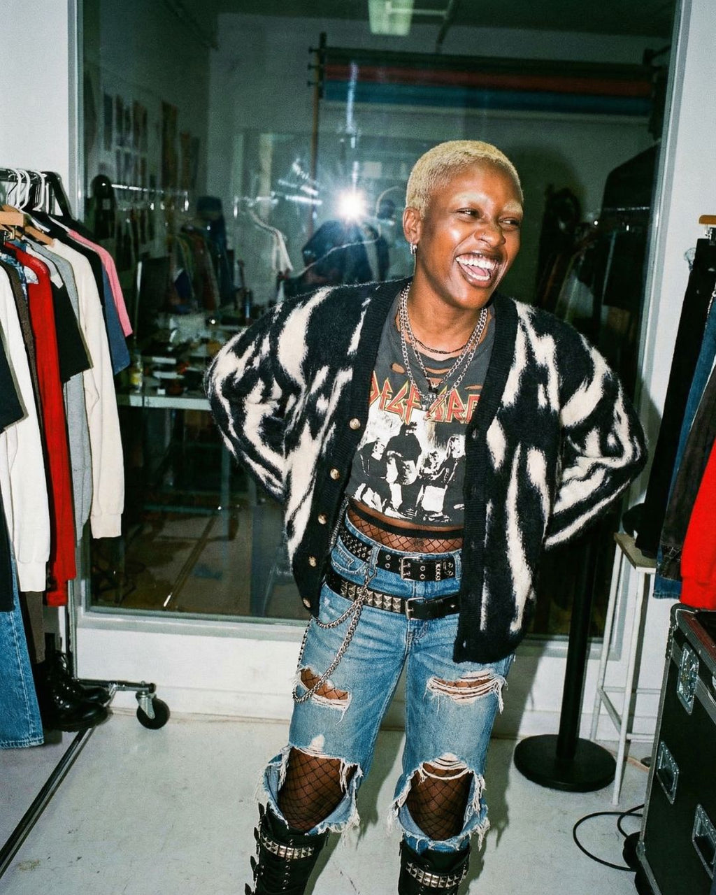 Woman wearing a the J cardigan, graphic t-shirt, and ripped jeans in a clothing store.
