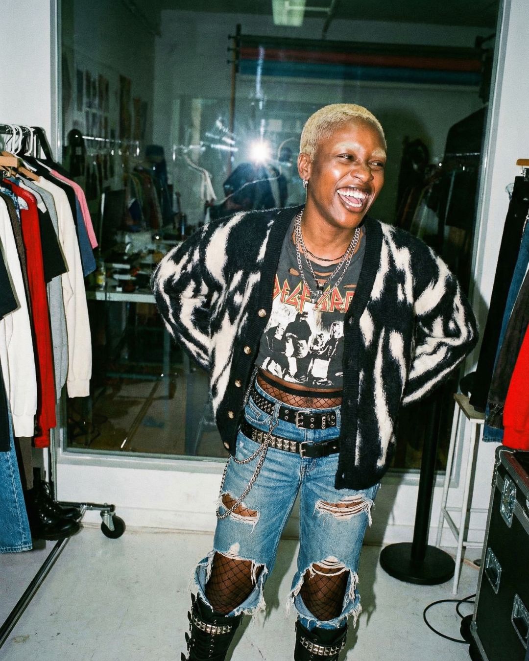 Woman wearing a the J cardigan, graphic t-shirt, and ripped jeans in a clothing store.